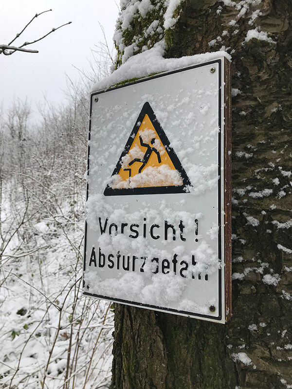 verschneites Schild "Vorsicht Absturzgefahr"