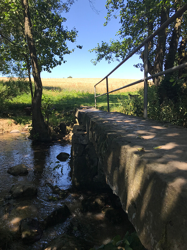 steinerne Brücke mit Geländer über den Bach
